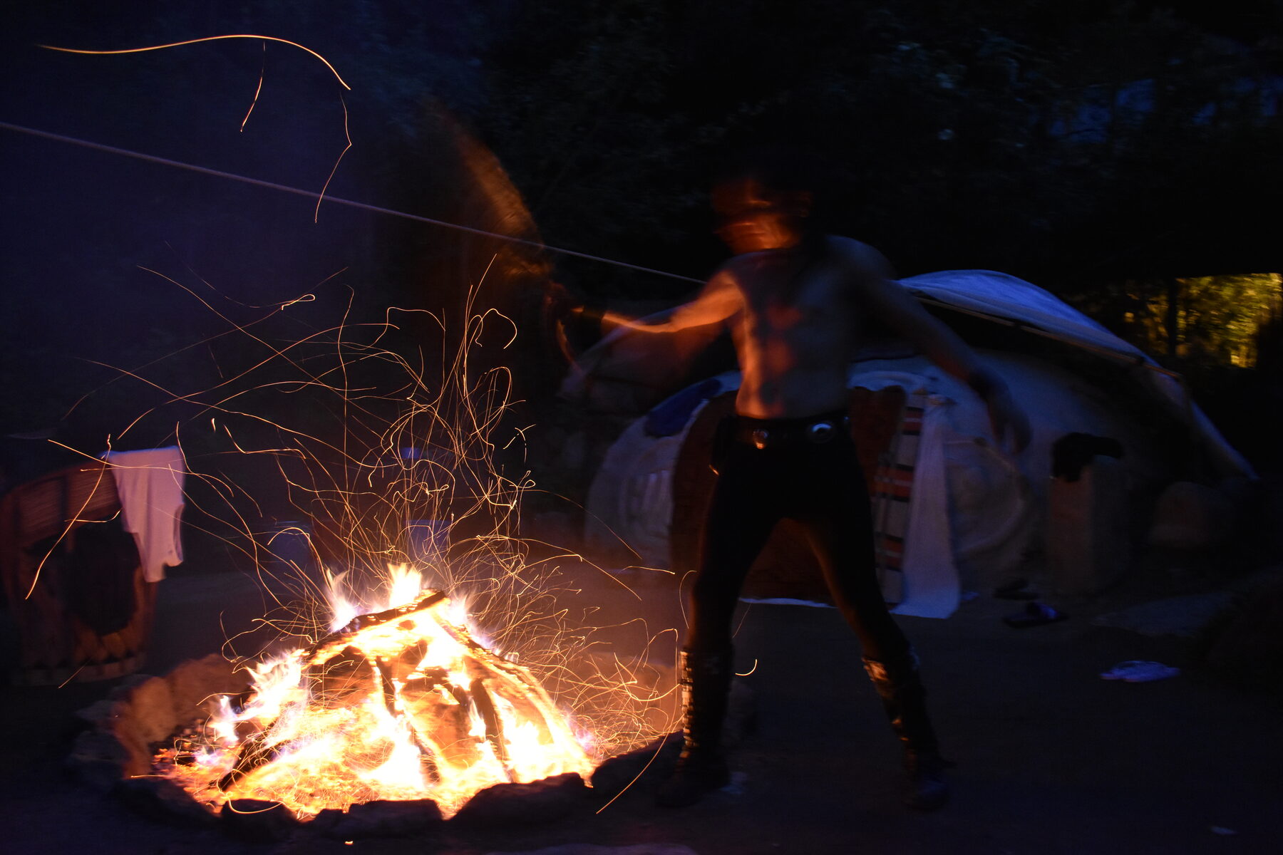 Fuego de temazcal de noche, con chispas y el recinto al fondo